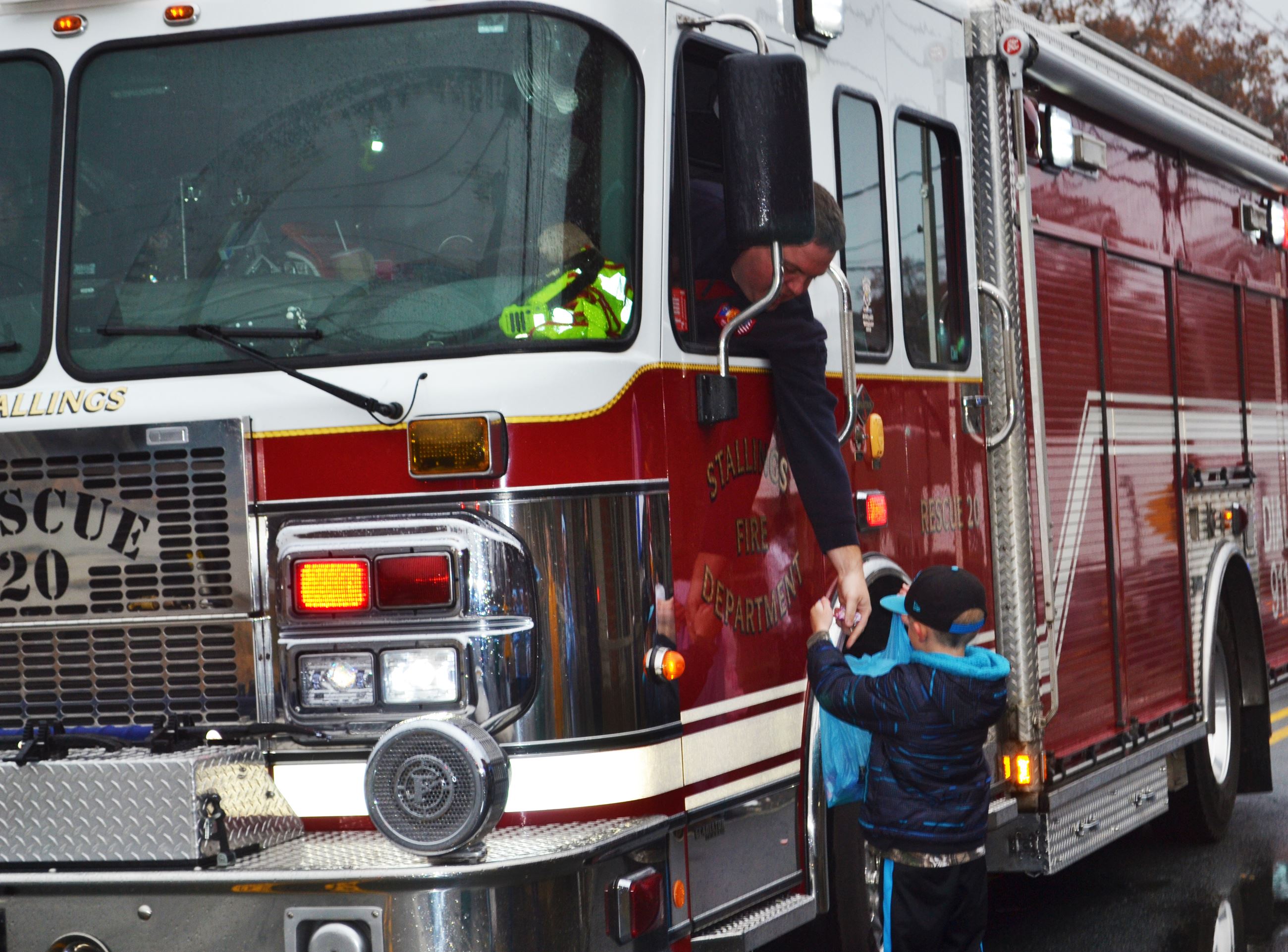 A firefighter hands candy to a child.